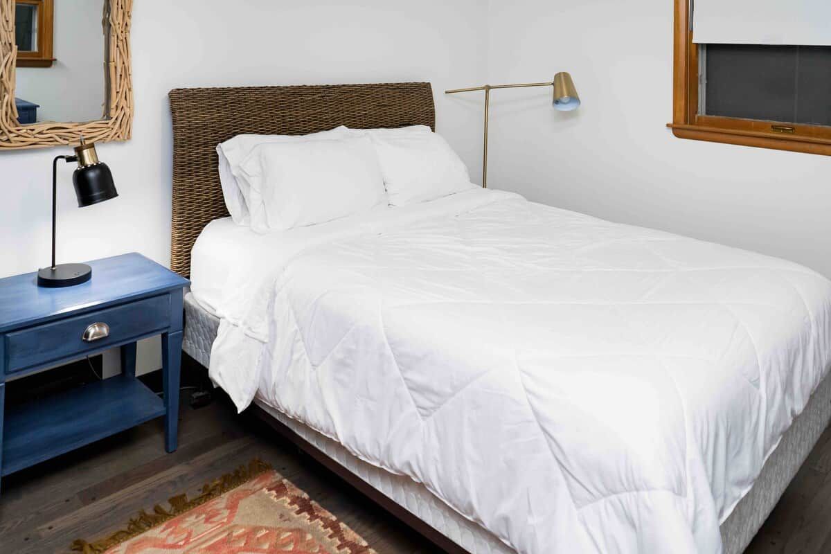 Une chambre à coucher avec un lit, une table de chevet, une lampe et un miroir au mur.
