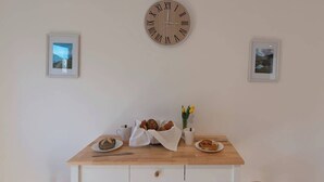 Una mesa de comedor con un reloj, cuadros enmarcados y una preparación para el desayuno.