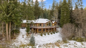Una cabaña con balcón, rodeada de árboles y nieve.