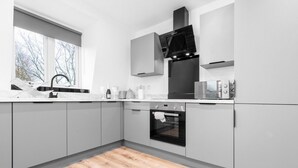 Una cocina moderna con armarios grises, horno empotrado y ventana que proporciona luz natural.
