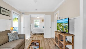 A living room with a sofa, coffee table, TV, and a view of the bedroom. -  Bungalow #3 - 2 Bed/1 Bath & Pool in Islamorada (Islamorada)