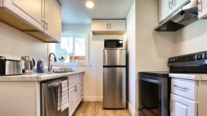 Una cocina moderna con electrodomésticos de acero inoxidable, armarios blancos y suelo de madera.