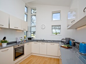 A modern kitchen with white cabinets, a microwave, a sink, and a clock on the wall. - 2 bedroom accommodation in Carbis Bay, near St Ives (Carbis Bay, near St Ives)
