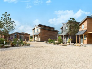 A modern residential area with multiple houses, a gravel driveway, and landscaped gardens.