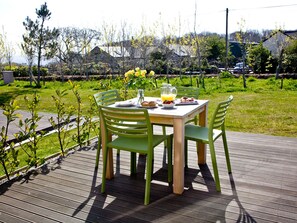 An outdoor dining area with a table and chairs, surrounded by greenery and trees.