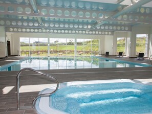 Ein überdachter Pool mit freiem Blick ins Freie, ein Fliesenboden und eine Metallleiter.