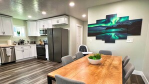 A modern kitchen with white cabinets, stainless steel appliances, and a wooden dining table with chairs.