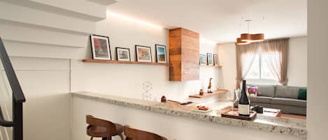 Uma cozinha moderna com bancada de granito, banquetas de madeira e adega embutida.