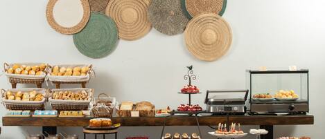 Montaje de bufé con diferentes alimentos y platos trenzados decorativos en la pared.