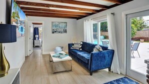 A living room with a blue sofa, a coffee table, and a painting on the wall. - Oasis Retreat! - 4BR/3BA Private Pool Home! (Fort Lauderdale)