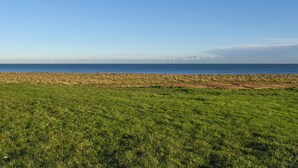 A grassy field with a clear view of the ocean and distant mountains. - A wonderful chalet set in a great seaside location. (Kessingland)