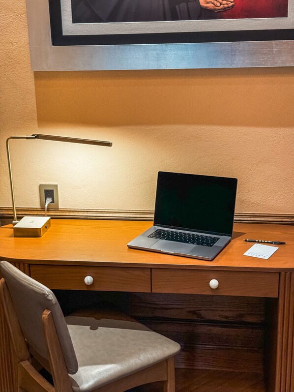 Un escritorio de madera con una computadora portátil, un bolígrafo y un bloc de notas.