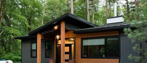 A modern house with a black exterior, wooden accents, and large windows.