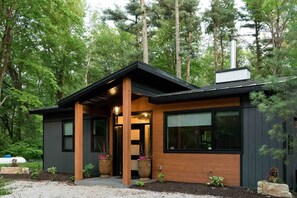 A modern house with a black exterior, wooden accents, and large windows. - •DRIFTWooD HAVEN• hot tub (Two Rivers)