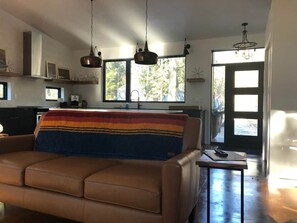 Un salon moderne avec un canapé, une table basse et des luminaires suspendus.