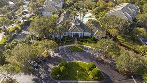 Vista aérea de un resort con varias edificaciones, una piscina central y jardines bien cuidados.