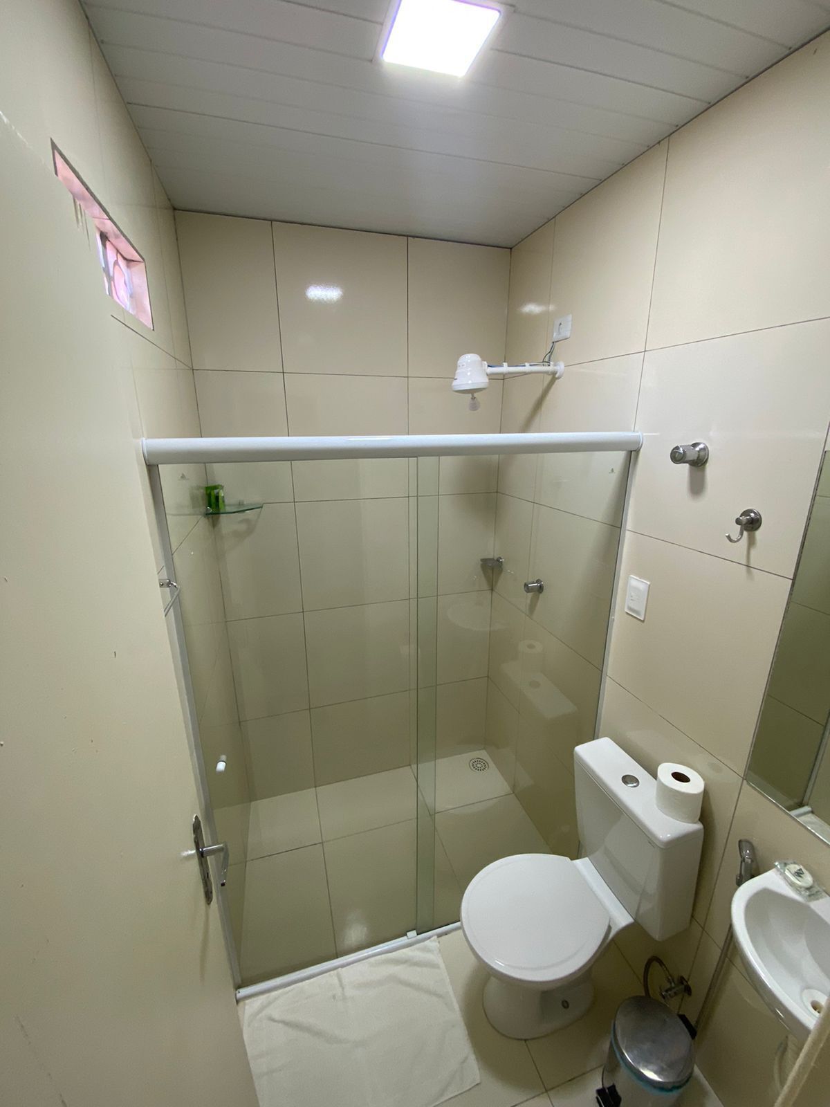 Un bagno piccolo e compatto con cabina doccia in vetro, un WC e un lavandino.
