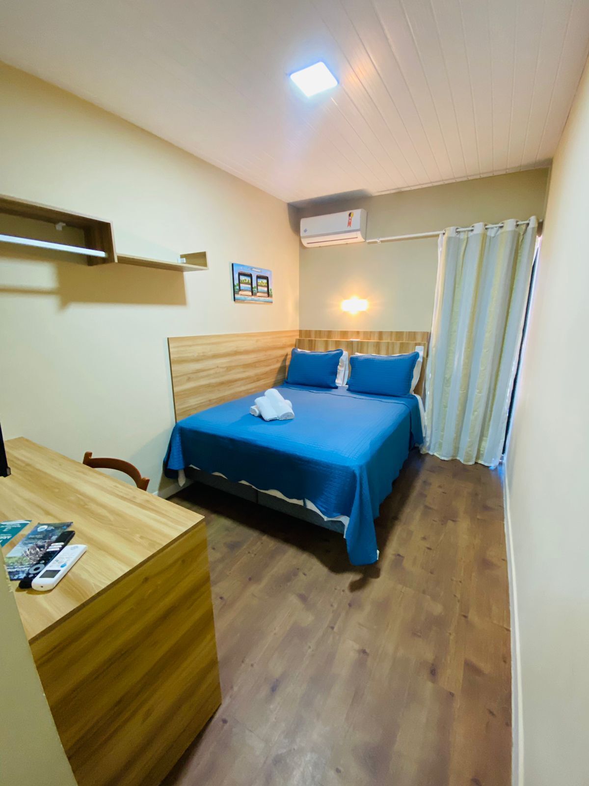 A small, tidy room with a single bed, a desk, and a shower curtain.