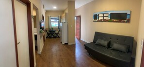 A hallway with a black leather sofa, a dining table with chairs, and a refrigerator. - Tamandaré Praia Hotel (Tamandaré)