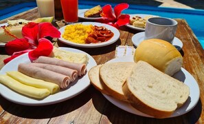 Un buffet de petit-déjeuner proposant divers plats, notamment des œufs, des saucisses, du pain et une boisson.