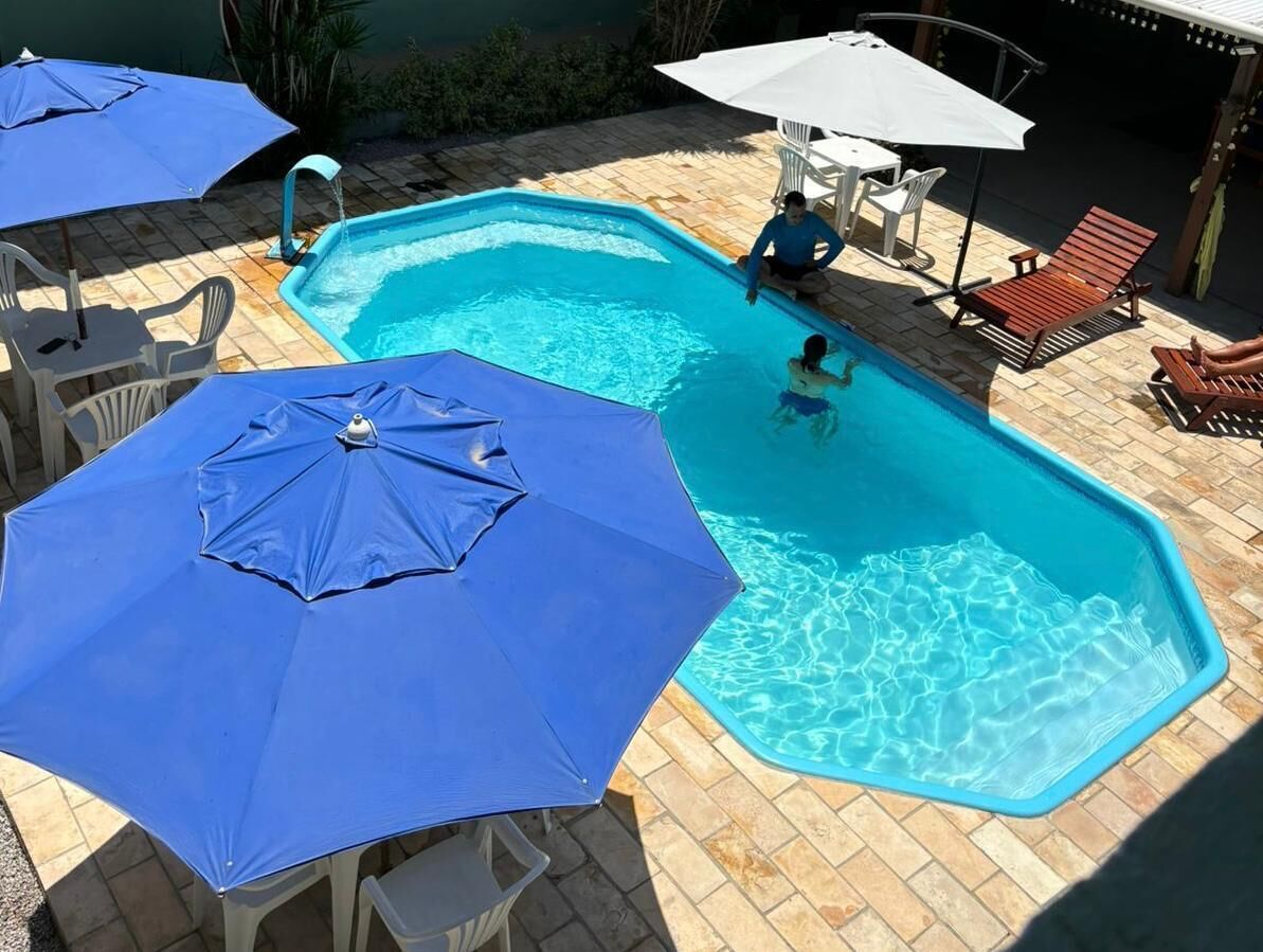 A swimming pool with blue umbrellas and lounge chairs.