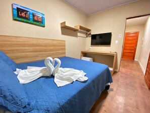 Une chambre d’hôtel avec un lit, un bureau, une télévision et une porte.