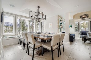A spacious dining area with a large table, multiple chairs, and a modern chandelier.