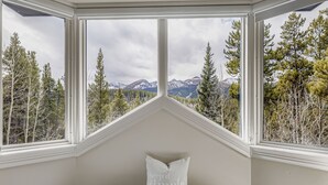 Ein Zimmer mit Blick auf eine gebirgige Landschaft durch große Fenster.
