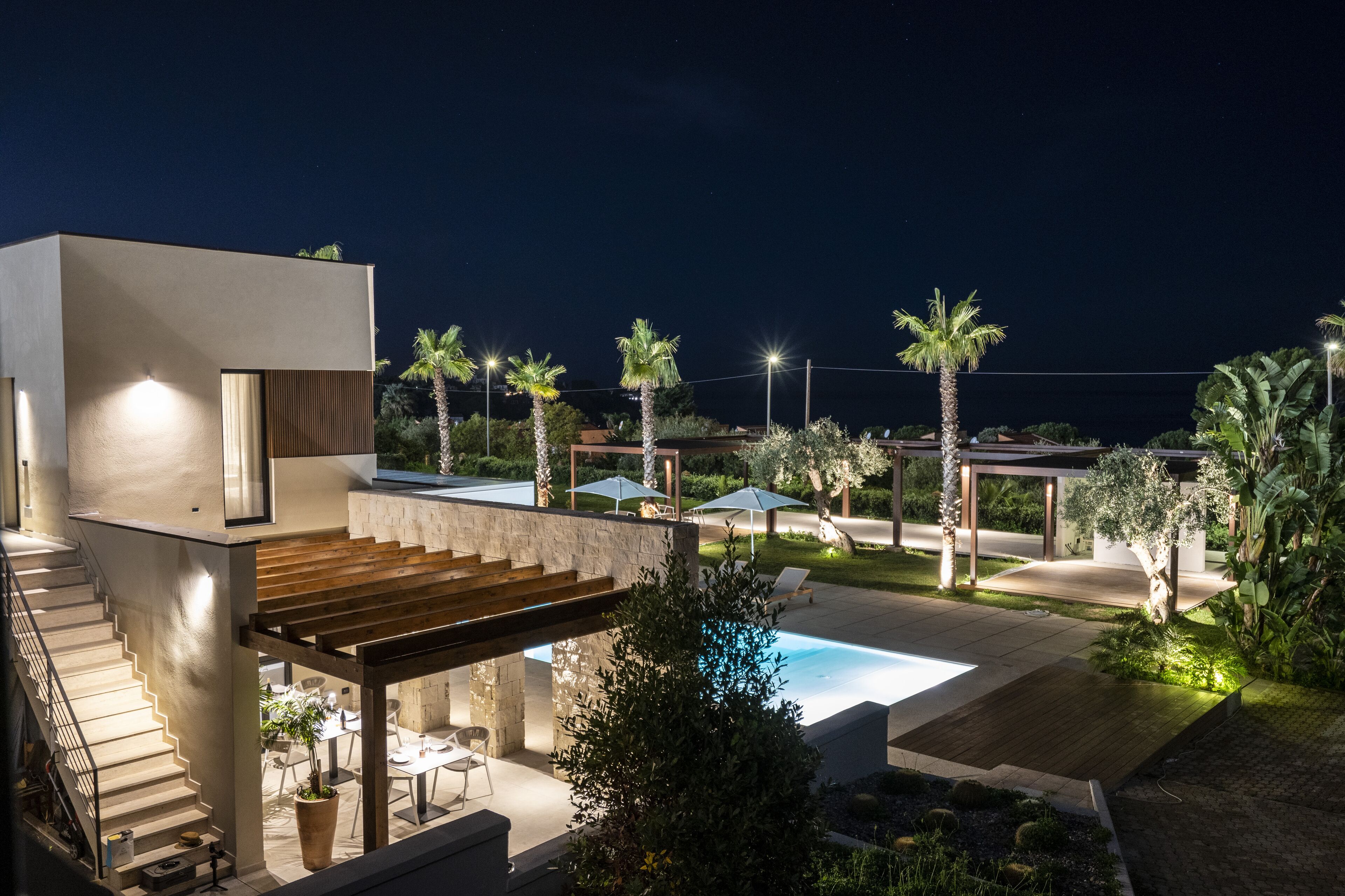 Una casa moderna con piscina, mobiliario exterior y palmeras.