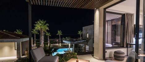 A modern outdoor seating area with a pool, palm trees, and a contemporary building.