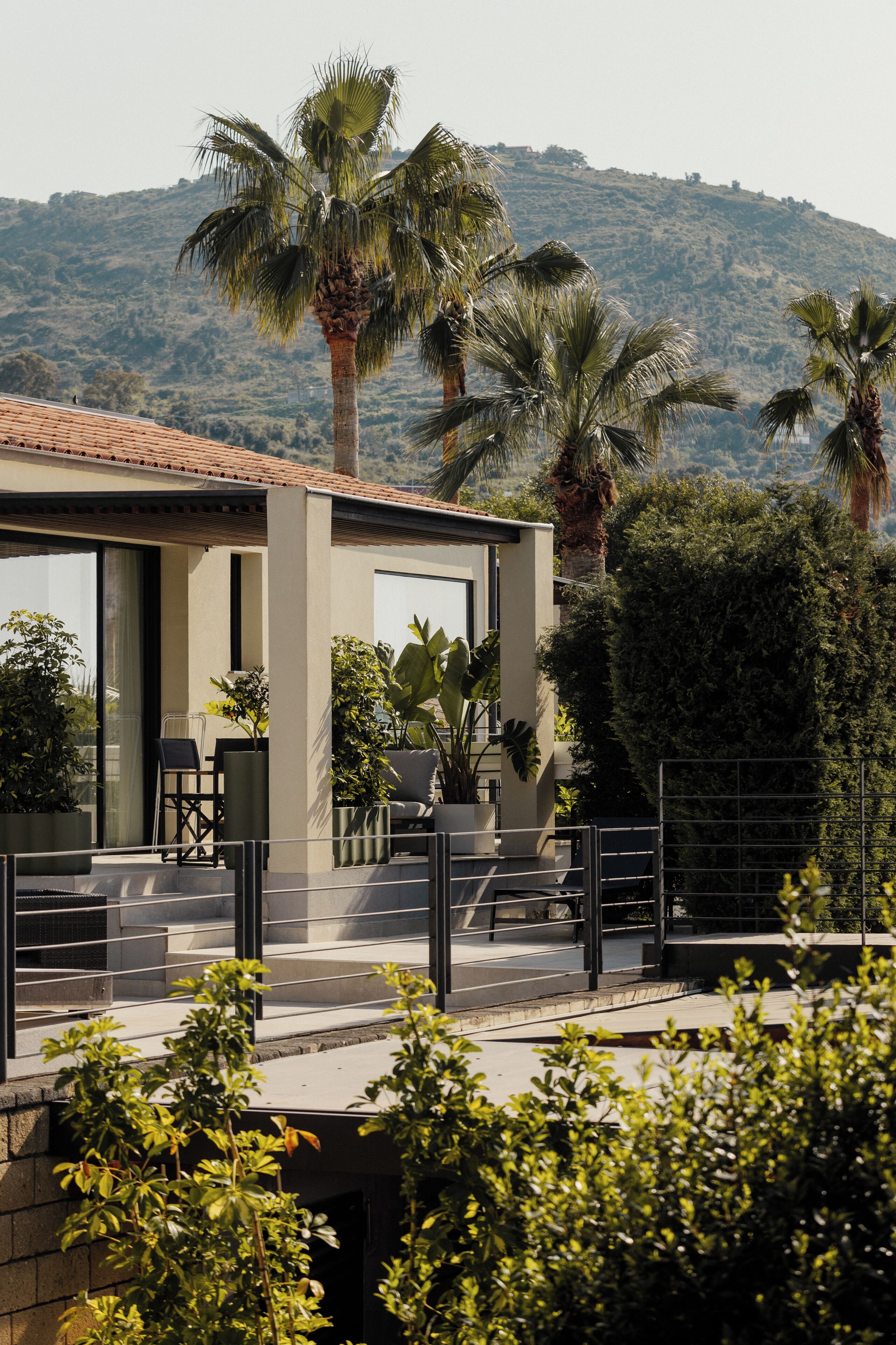 Un bâtiment moderne doté d’un toit plat, de grandes fenêtres et d’un balcon aménagé avec du mobilier d’extérieur.
