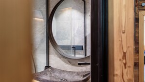 A bathroom with a round mirror, a curved sink, and a wooden door. - Immodreams - Le Billat - Avoriaz (Avoriaz)
