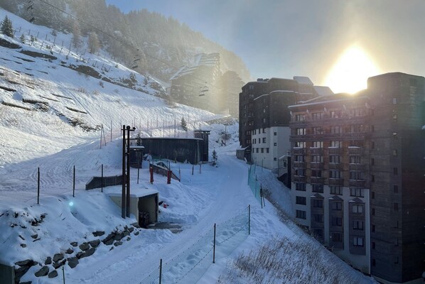 A snow-covered ski resort with a ski lift, buildings, and a clear sky.