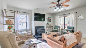 Un salon avec une cheminée, un ventilateur de plafond et un téléviseur.