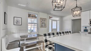 Une cuisine moderne dotée d’un grand îlot central, de meubles blancs et de banquettes à motifs à carreaux noirs et blancs.