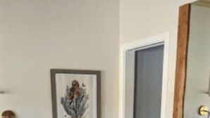 Une pièce avec un canapé en cuir marron, un tapis à motifs et une œuvre d’art encadrée accrochée au mur.