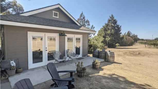 Une maison dotée d’un patio, d’un espace salon extérieur et offrant une vue sur un vignoble.