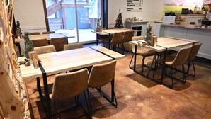 A restaurant with multiple tables and chairs, a Christmas tree, and a menu board on the wall.