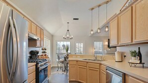 A modern kitchen with stainless steel appliances, wooden cabinets, and pendant lighting. - Rustic Aggie: 9 Min to Kyle Field + Pet-Friendly (Bryan)