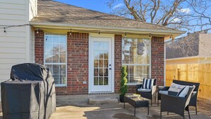 A covered patio with outdoor furniture, a barbecue grill, and a wooden fence. - Rustic Aggie: 9 Min to Kyle Field + Pet-Friendly (Bryan)