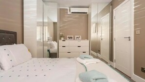 A bedroom with a bed, bedside tables, a dresser, and a wardrobe. - Luxury London Garden Flat (London)