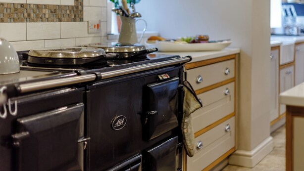 A kitchen with a black stove, wooden cabinets, and a tiled backsplash.