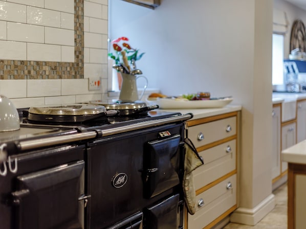 A kitchen with a black stove, wooden cabinets, and a tiled backsplash.