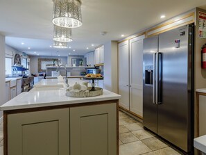 A modern kitchen with a central island, stainless steel refrigerator, and pendant lighting.