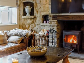 A cozy living room with a stone fireplace, a television mounted above it, and a comfortable sofa with cushions. - 7 bedroom accommodation in Llandegla, near Wrexham (Llandegla, near Wrexham)
