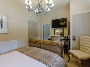 A bedroom with a wooden bed, a chair, a desk, a television, and a chandelier. - 7 bedroom accommodation in Llandegla, near Wrexham (Llandegla, near Wrexham)