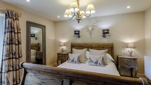 A bedroom with a wooden bed, a mirror, a chandelier, and two bedside tables with lamps.