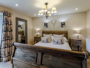 A bedroom with a wooden bed, a mirror, a chandelier, and two bedside tables with lamps.