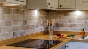 A kitchen with a tiled backsplash, wooden countertop, and stainless steel appliances.