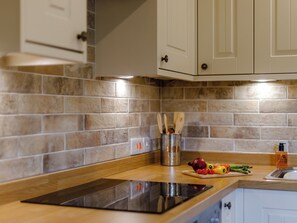 A kitchen with a tiled backsplash, wooden countertop, and stainless steel appliances.